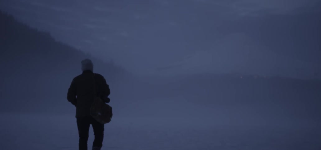 A person is walking down the foggy field