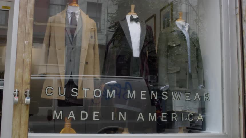 A menswear shop window display on a busy street