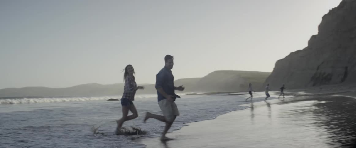 Man and woman run from the waves at the beach