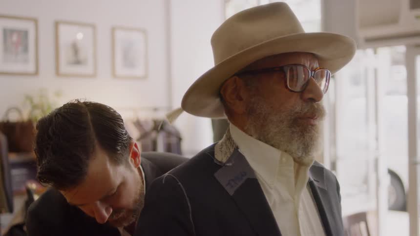 Tailor adjusts a bearded man's suit