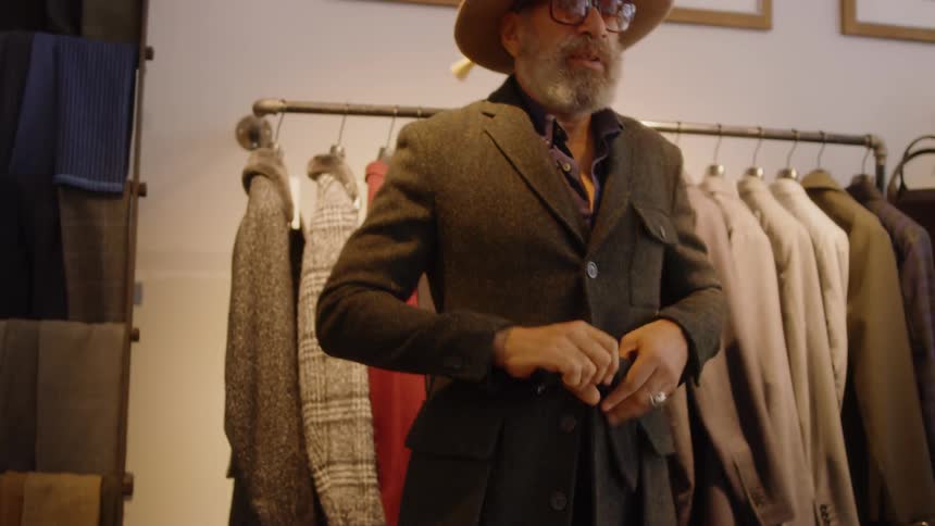 A man wearing a hat adjusts his jacket