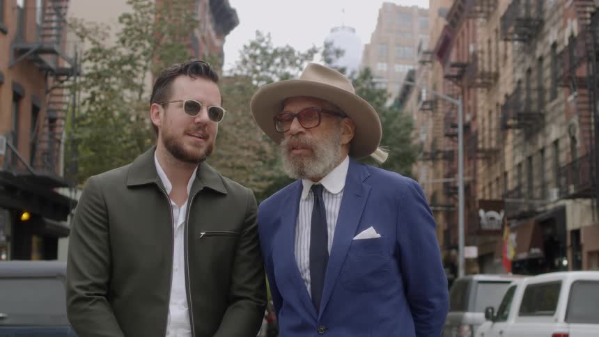 Two men talk and stand in the street together