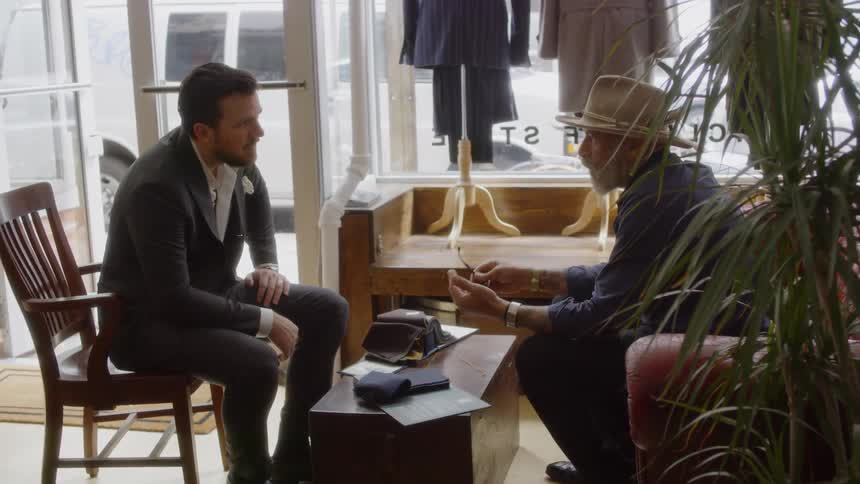 Two men sit and talk in a clothing store