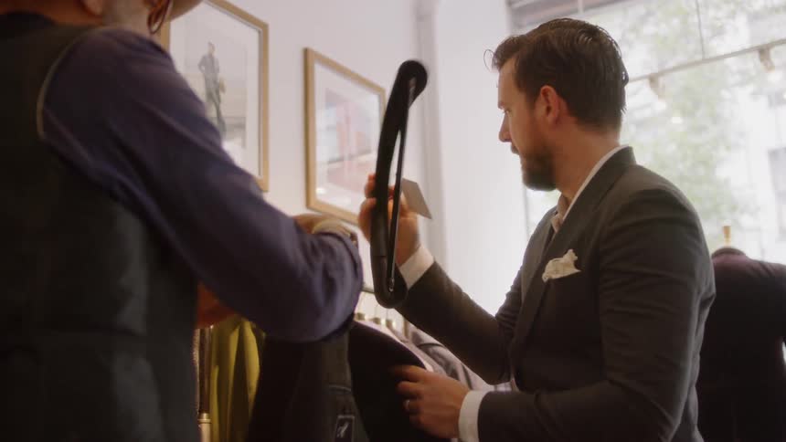 A man tries on a suit jacket in a clothing store