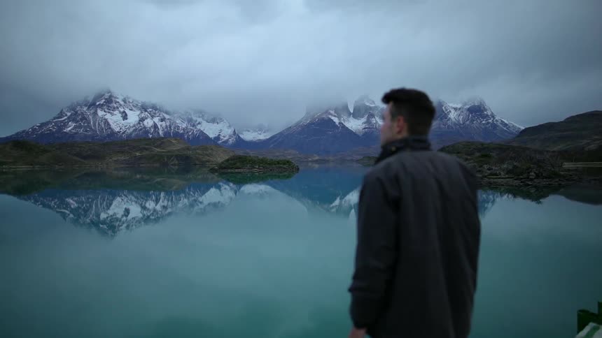A man stands on the pier by the lake