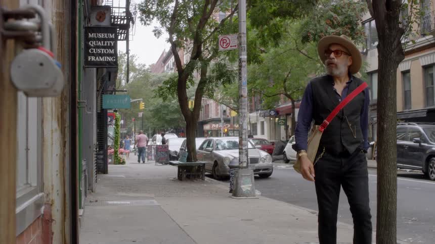 A man wearing a hat stops walking and looks at a store