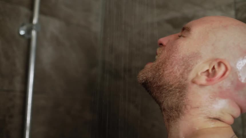 A man is drinking water as it pours over him in a shower