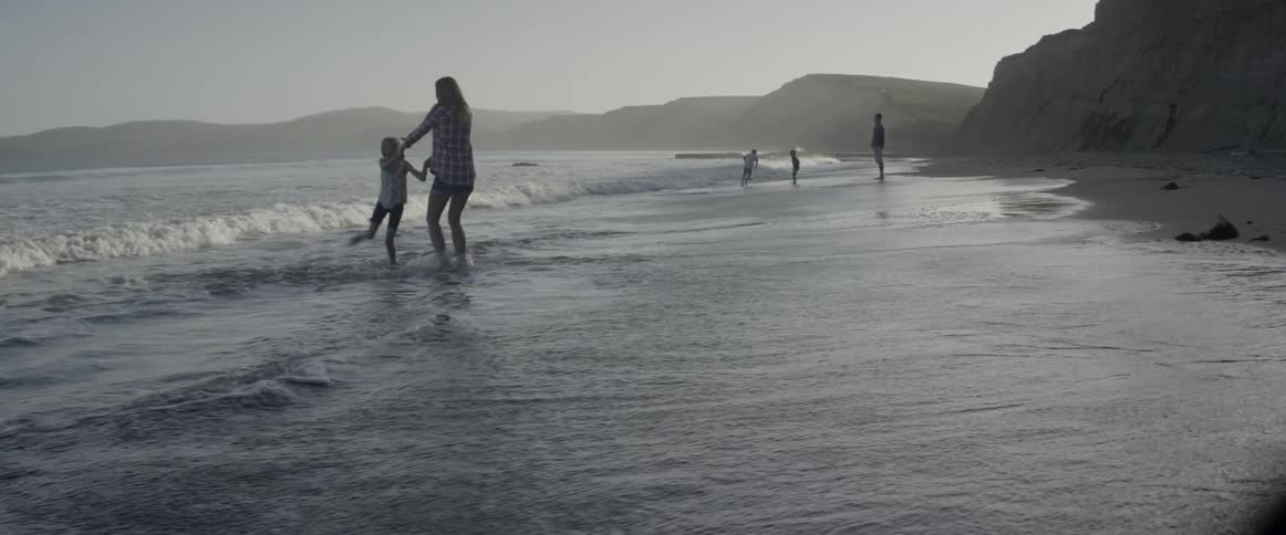 A family is playing in the water by the beach