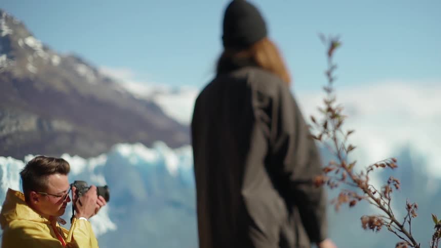 A man takes a photograph near glaciers