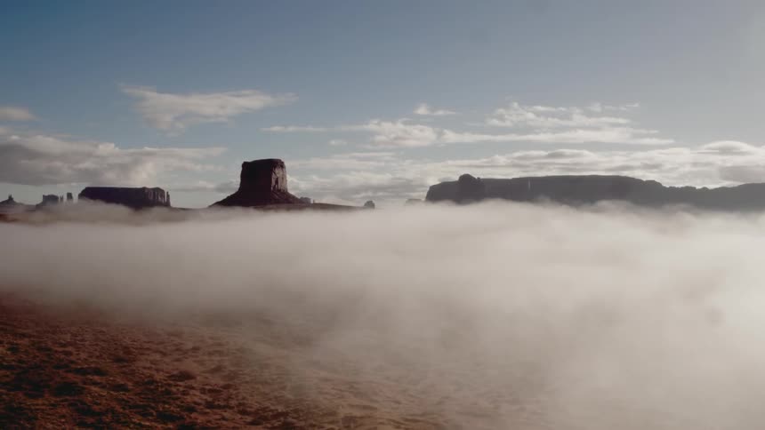 Mist floats near the mountains under a blue sky