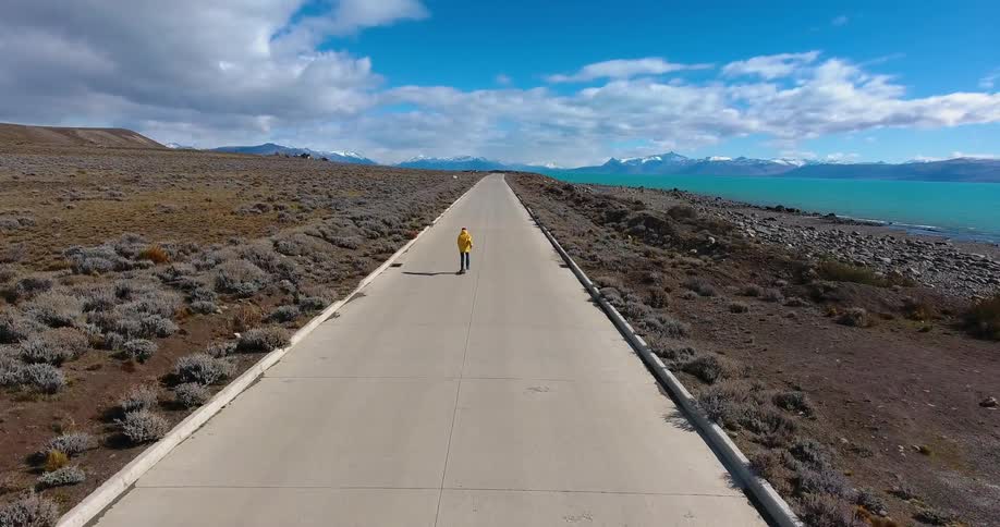 A man skateboards towards a mountain lake