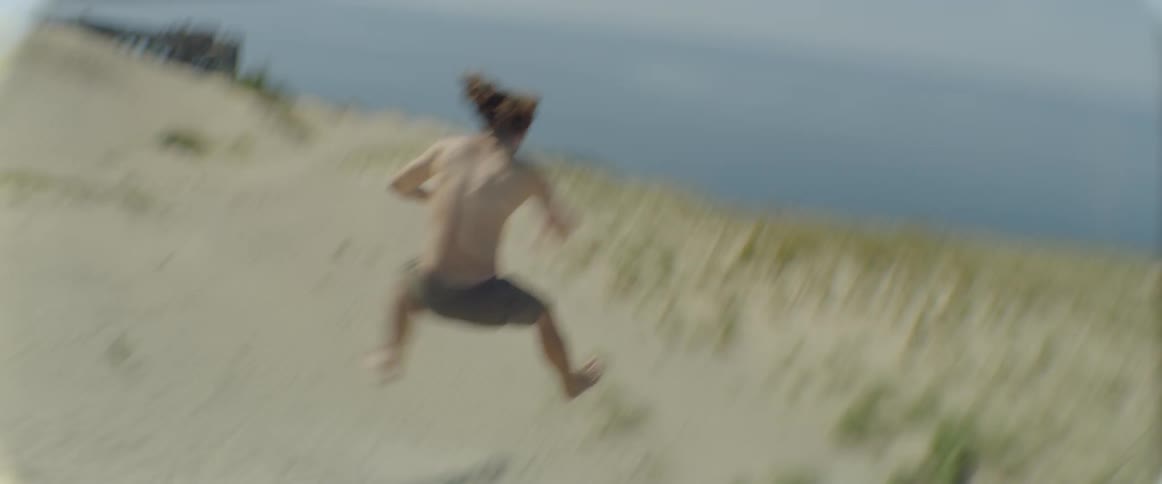 A man runs and jumps over a ledge on a beach