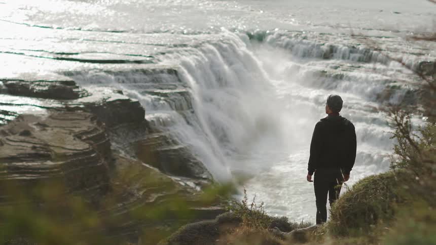 A man looks at a waterfall