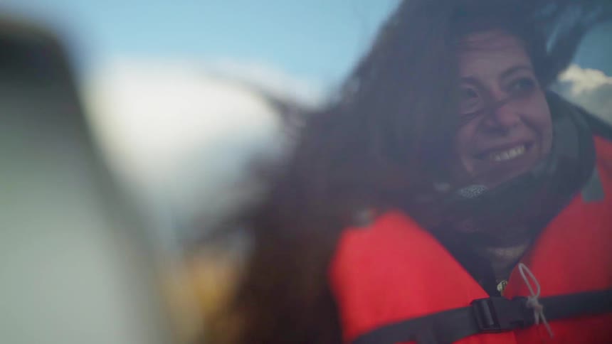 A woman smiles while riding in a boat