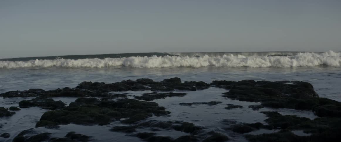 The waves crash against the shore reaching the surf