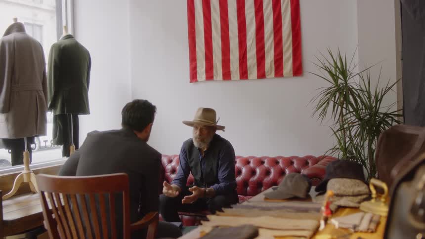 Two men sit in a store facing each other talking