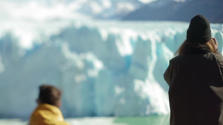 People look across the water at an iceberg