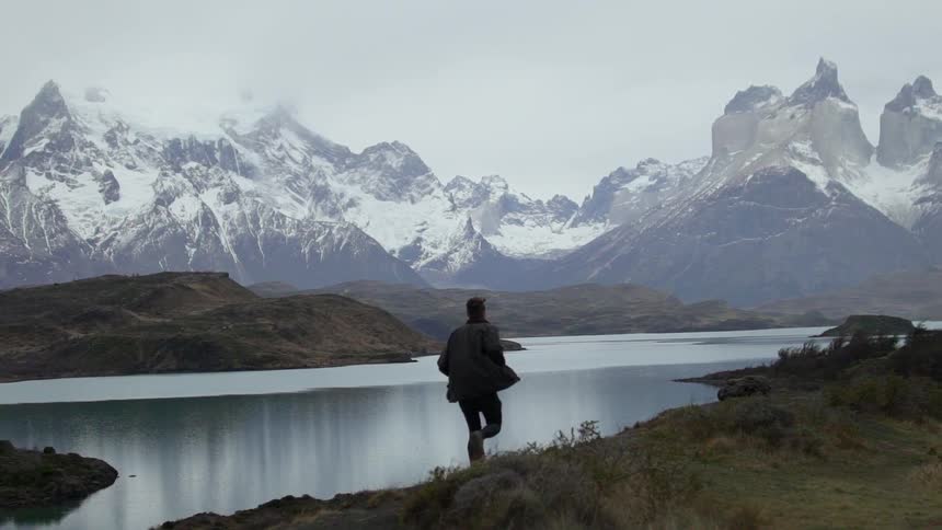 A man runs on a trail overlooking a mountain lake