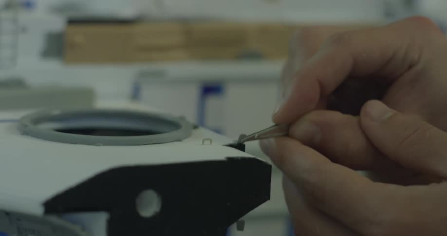 A man uses tweezers to work on a model