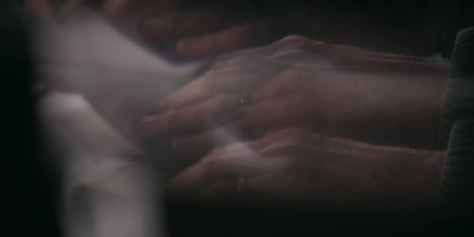 A person writes on paper with a pen