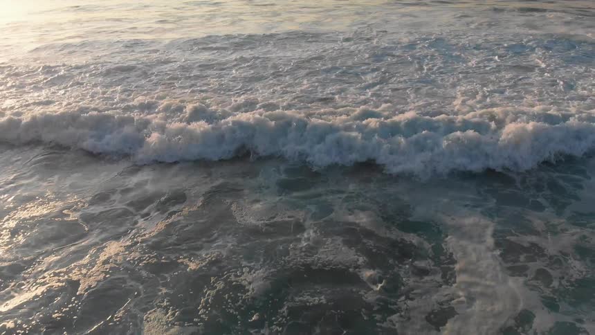 Ocean waves wash ashore at sunset