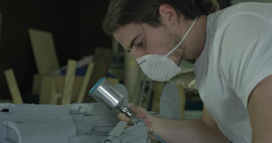 Man wears a mask as he works with an implement