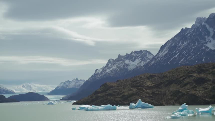 Chunks of ice sit in the lake near the mountains