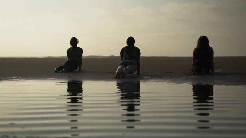 Women do yoga on a beach