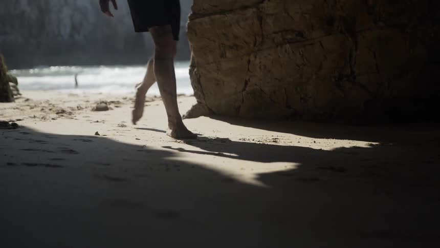 A person walks into the cave from the beach