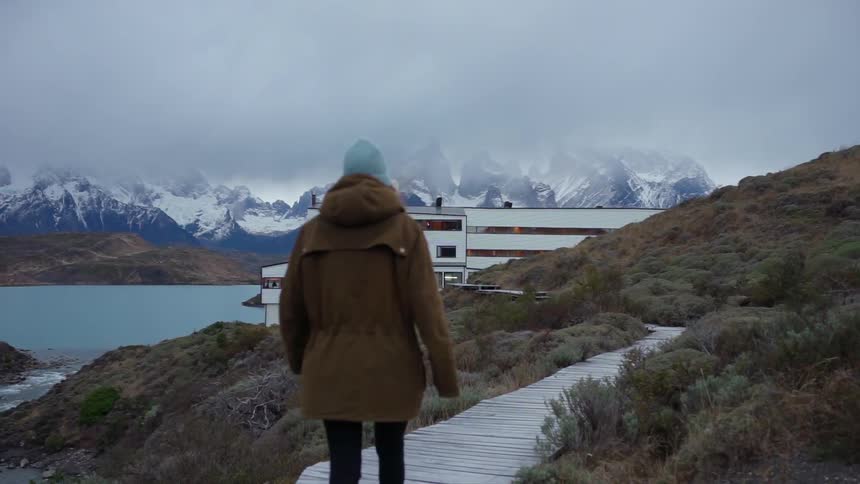 A woman is walking on a wooden trail outside in winter