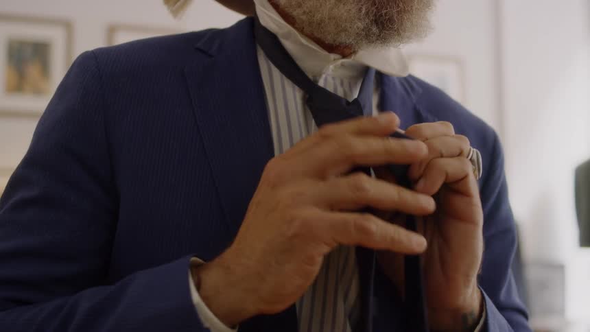 Bearded man ties his tie