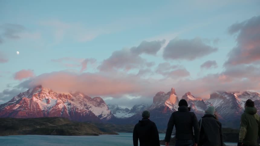 Hikers looks at snowy mountains at sunset
