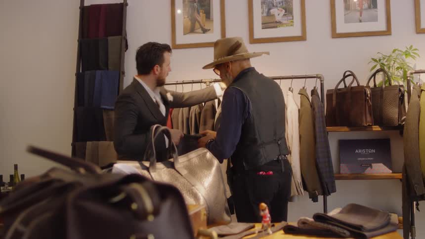 A salesman helps a customer try on a jacket