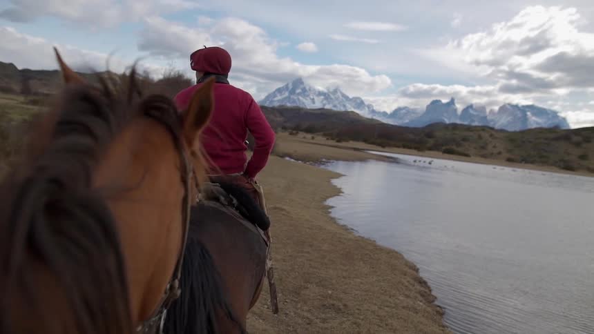 Horses are ridden next to a mountain lake