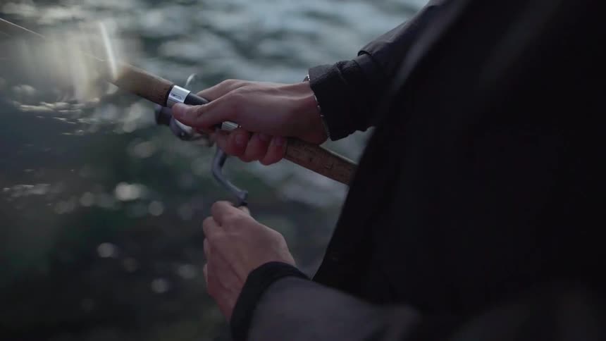 A man moves his fishing pole and line over the water