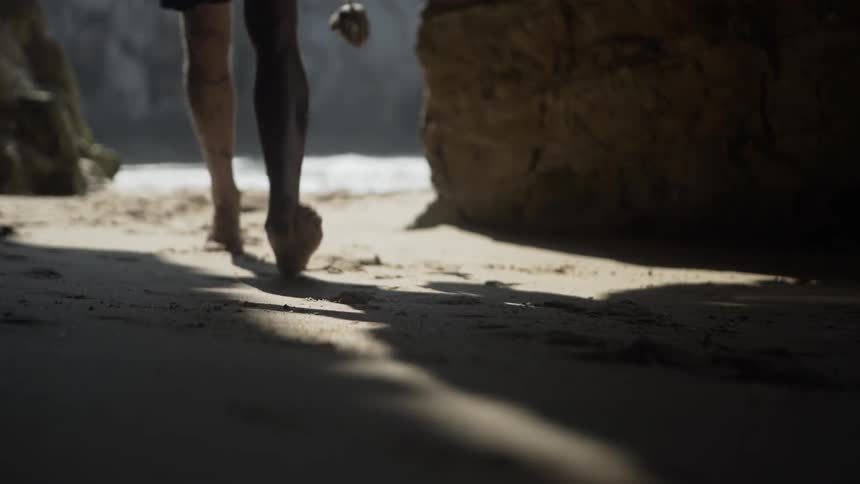 A person walks from the beach into the cave