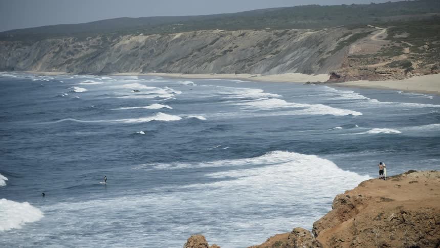 A paddle boarder paddles out over a wave
