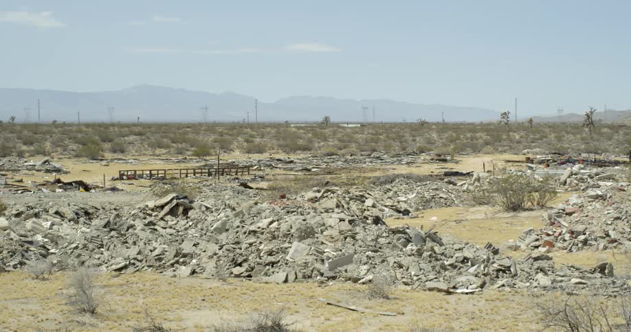 The field is covered with debris before the road in the distance