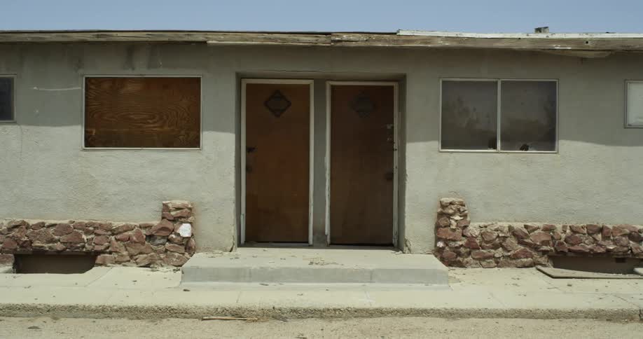 A run down motel has a boarded up window