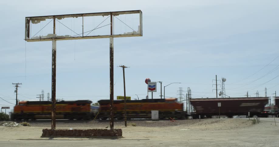 A train is passing through a rundown rural area in daylight
