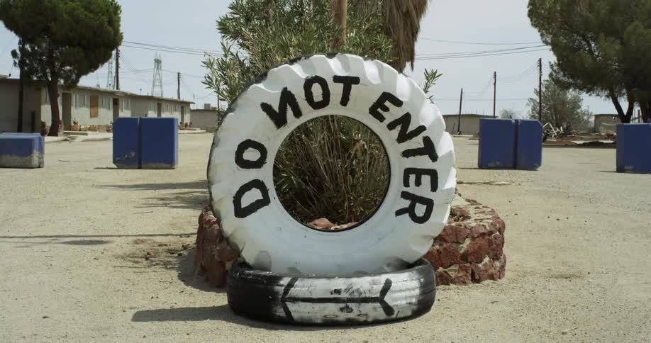 Large tire with painted words on it sits atop a smaller tire