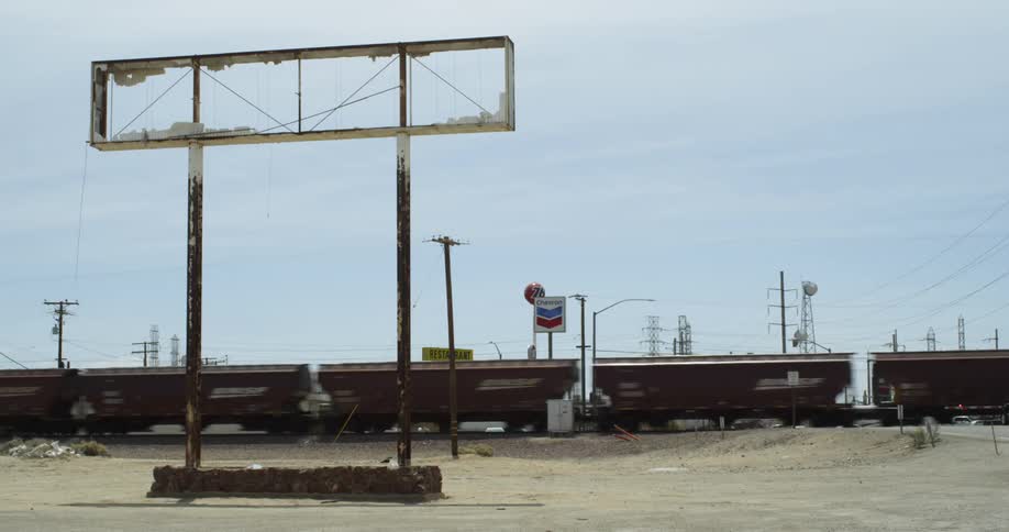A train drives by a rural gas station