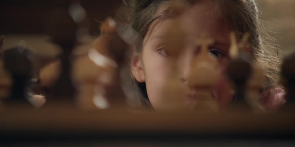 Child stares at some chess pieces