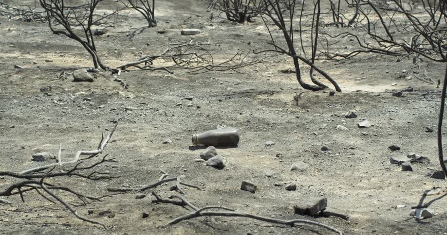 There is a single bottle on the ground with the rocks