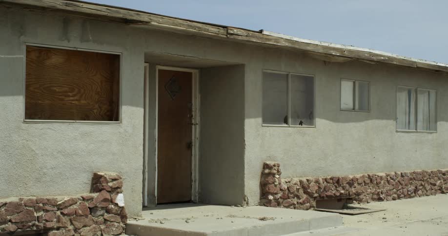 An old motel has a boarded up window