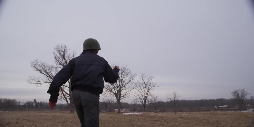 Boy running across a field on a cloudy day