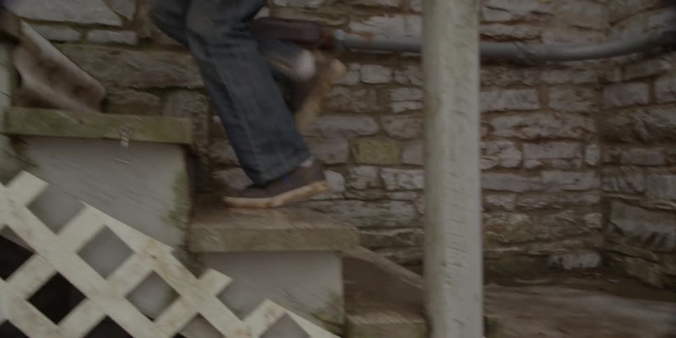 Tight shot of someone running up stone stairs and entering a doorway