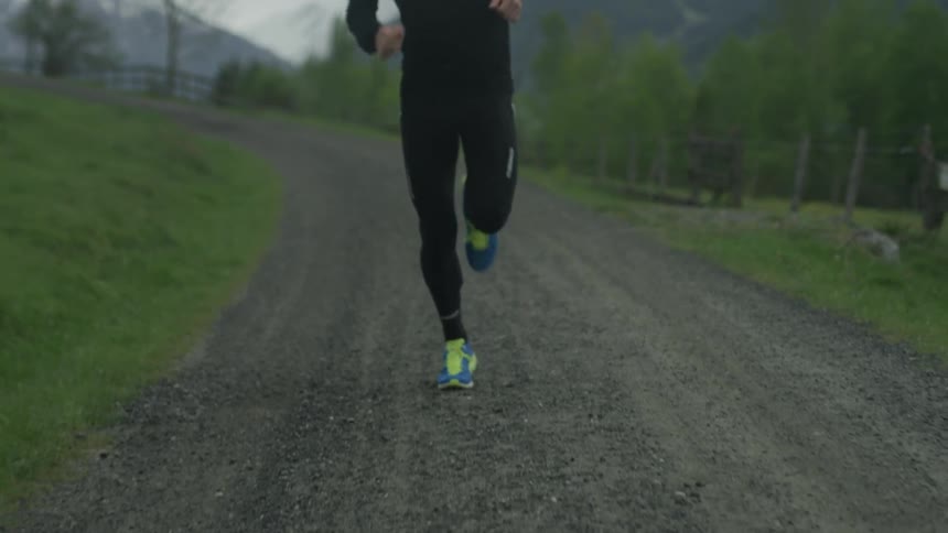 A man is jogging on a dirt trail under cloudy skies