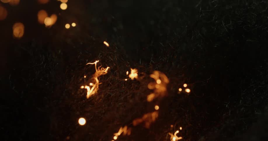 Fire burns up grass and twigs at night
