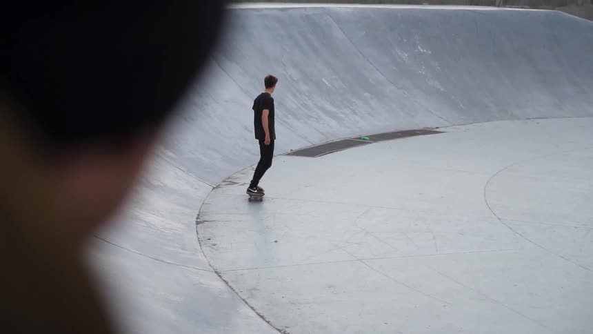 A man skateboards in a concrete bowl